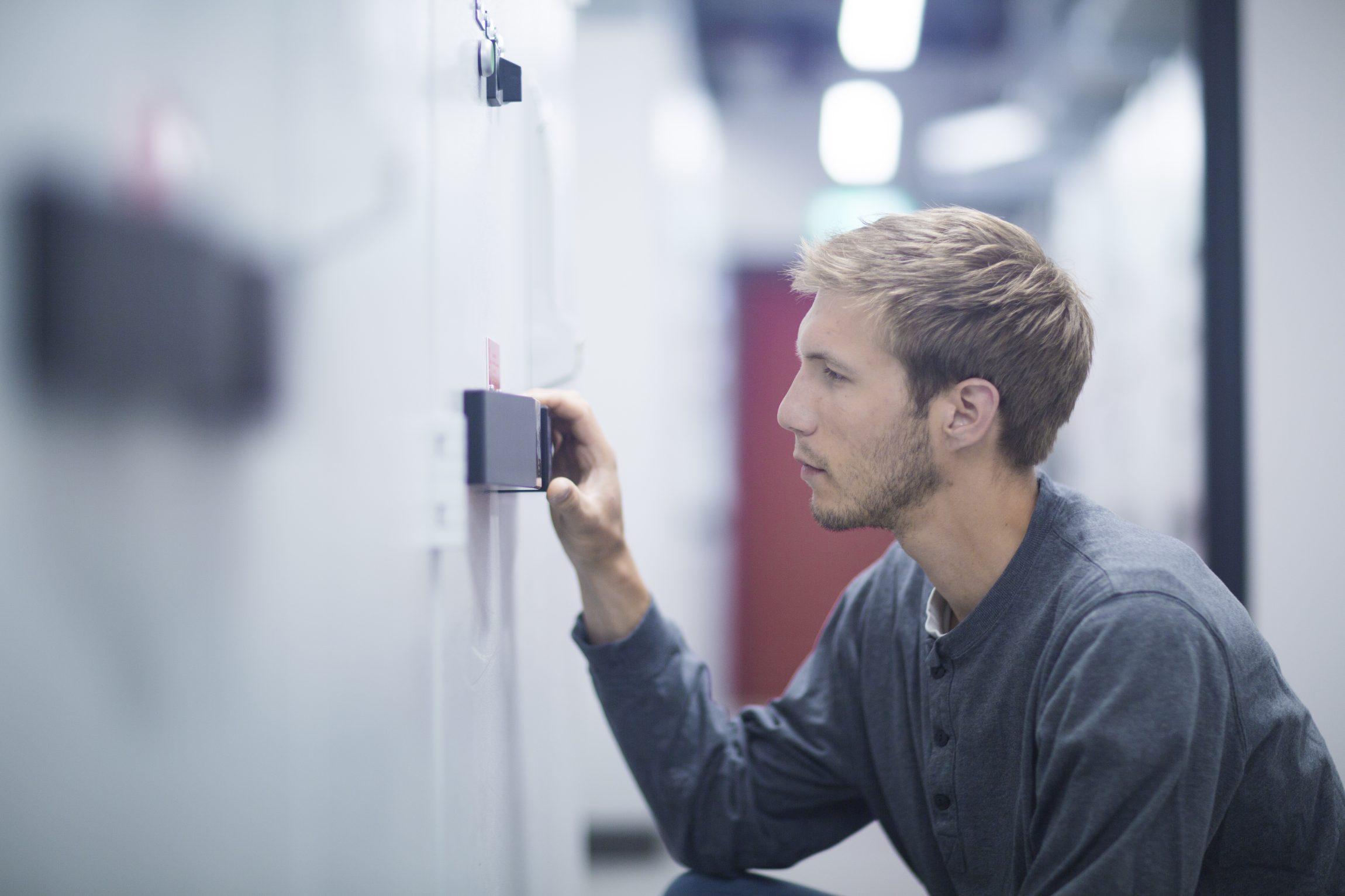 Male technician crouching to turn switch in technical room